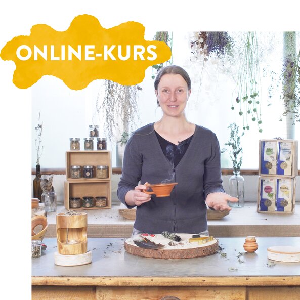 Zu sehen ist eine Frau in einer Küche mit sehr vielen Kräutern. Sie hält eine Räucherkanne in der Hand.