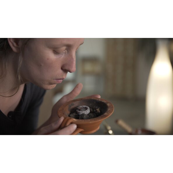 Zu sehen ist eine Frau die an der Räucherkanne, in der Räucherkohle liegt, riecht. | © Florian Bauer